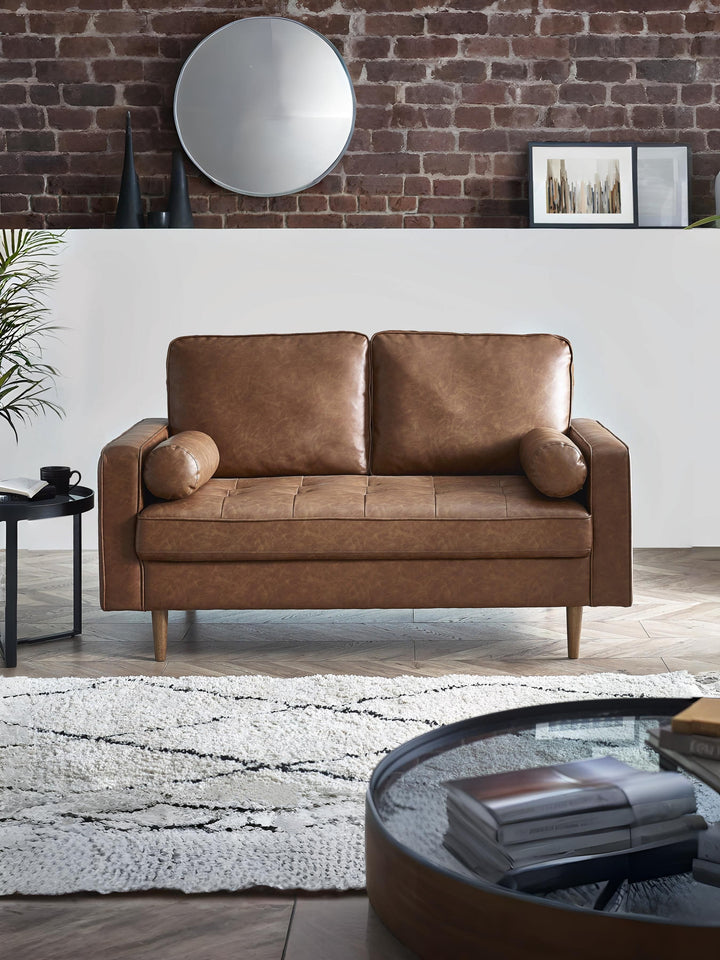 Brown tan faux leather Henley 2 seater sofa with bolster cushions by Julian Bowen, shown in a stylish living room setting.